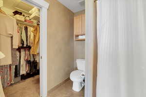 Bathroom with tile patterned flooring, toilet, visible vents, baseboards, and a walk in closet