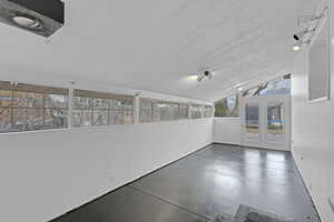 Unfurnished sunroom featuring lofted ceiling