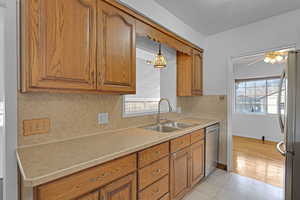 Kitchen with a ceiling fan, appliances with stainless steel finishes, brown cabinets, light countertops, and a sink