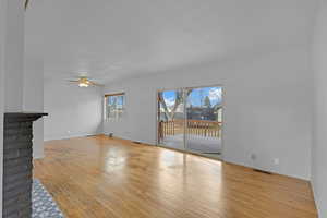 Unfurnished living room with light wood-style floors, visible vents, baseboards, and a ceiling fan