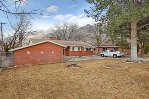 Exterior space featuring brick siding, a chimney, a front yard, fence, and driveway