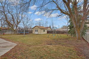 View of yard featuring a fenced backyard, a trampoline, a playground, and an outdoor structure