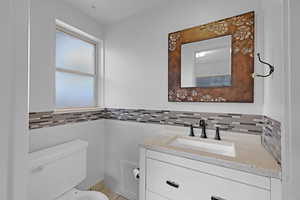 Bathroom featuring tasteful backsplash, vanity, and toilet