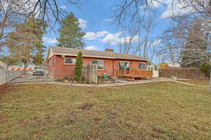 Back of property with brick siding, a yard, a chimney, a gate, and fence