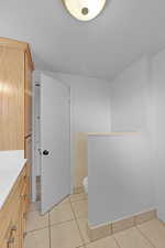 Bathroom with tile walls, toilet, vanity, a textured ceiling, and tile patterned floors