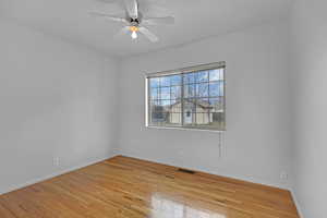 Unfurnished room featuring ceiling fan, light wood-type flooring, visible vents, and baseboards