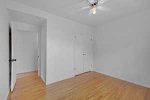 Unfurnished bedroom with light wood finished floors, baseboards, and a ceiling fan