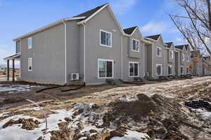 Snow covered back of property with entry steps, a residential view, and stucco siding