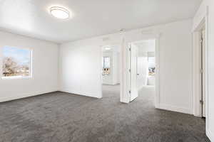 Unfurnished room with dark colored carpet, visible vents, and baseboards