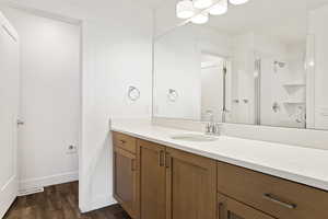 Bathroom featuring wood finished floors, vanity, visible vents, baseboards, and a shower stall