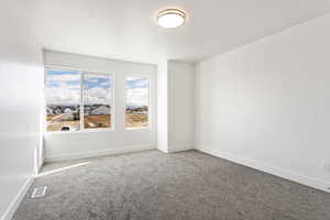 Carpeted spare room with visible vents and baseboards