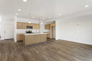 Kitchen with stainless steel appliances, a sink, light countertops, dark wood-style floors, and a center island with sink