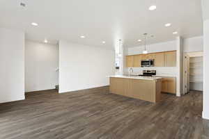 Kitchen featuring a center island with sink, visible vents, dark wood-style flooring, stainless steel appliances, and light countertops