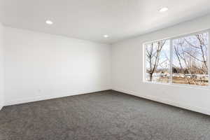 Spare room with dark colored carpet, baseboards, and recessed lighting