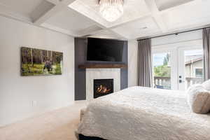 Bedroom with coffered ceiling, a large fireplace, carpet flooring, and baseboards
