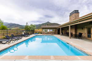 Pool featuring a patio area, a mountain view, and fence