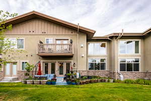 Rear view of house with a balcony, stone siding, and stucco siding