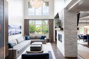 Living room with a fireplace, a notable chandelier, a high ceiling, and wood finished floors