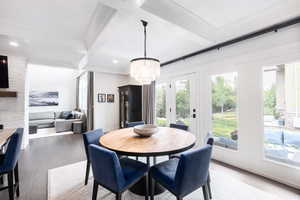 Dining space featuring an inviting chandelier, light wood-style flooring, coffered ceiling, and beam ceiling