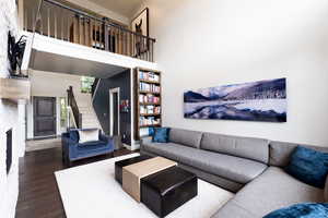 Living room with stairs, a fireplace, wood finished floors, and a towering ceiling