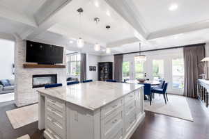 Kitchen with dark wood-style floors, light stone counters, a fireplace, open floor plan, and white cabinetry