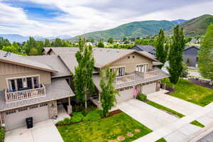 View of front of house featuring board and batten siding, concrete driveway, a shingled roof, and a balcony