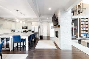 Kitchen with beverage cooler, stainless steel appliances, dark wood-type flooring, and open floor plan