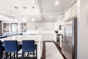 Kitchen featuring decorative backsplash, coffered ceiling, appliances with stainless steel finishes, beamed ceiling, and a sink