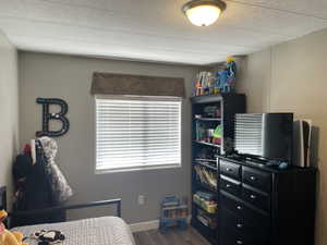 Bedroom with a textured ceiling, baseboards, and wood finished floors