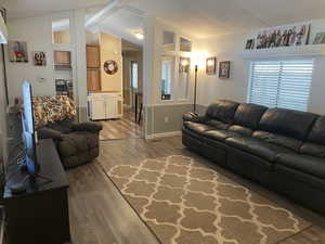 Living area featuring vaulted ceiling with beams, baseboards, and wood finished floors