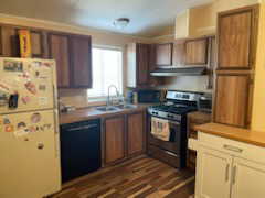 Kitchen with black dishwasher, freestanding refrigerator, stainless steel range with gas stovetop, a sink, and under cabinet range hood