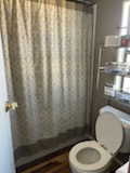 Full bathroom featuring a shower with curtain and toilet