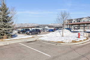 Snow covered parking area with a residential view, a mountain view, and covered and uncovered parking