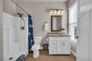 Bathroom featuring toilet, a shower with shower curtain, wood finished floors, vanity, and baseboards