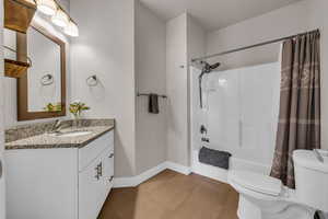 Bathroom featuring baseboards, toilet, wood finished floors, shower / bath combination with curtain, and vanity