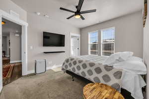 Carpeted bedroom with a ceiling fan, visible vents, and baseboards