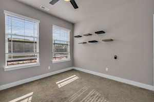 Carpeted empty room with ceiling fan, visible vents, and baseboards