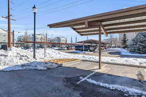 Snow covered parking area with covered parking and a residential view