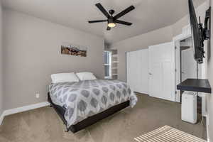 Carpeted bedroom featuring a ceiling fan, a closet, visible vents, and baseboards