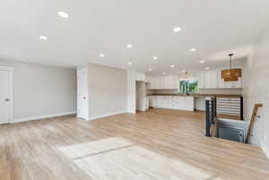 Unfurnished living room with sink and light wood-type flooring