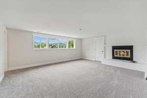 Unfurnished living room with light colored carpet and a fireplace