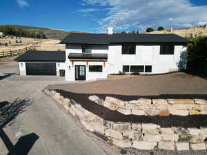 Modern inspired farmhouse with concrete driveway, a standing seam roof, an attached garage, and fence