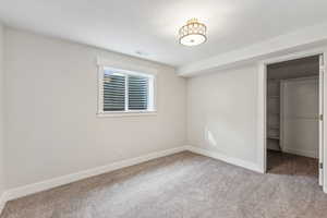 Unfurnished bedroom featuring a spacious closet, a closet, and carpet flooring