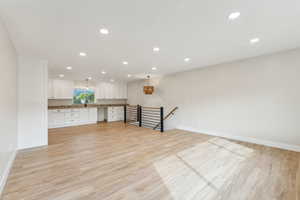 Unfurnished living room with sink and light wood-type flooring