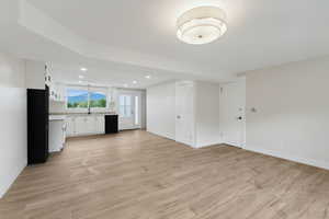 Interior space featuring white cabinetry, sink, light wood-type flooring, and black appliances