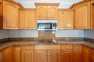 Kitchen featuring black electric stovetop, stainless steel microwave, and dark stone countertops