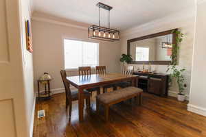 Dining area with a healthy amount of sunlight, visible vents, dark wood finished floors, and crown molding