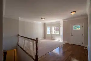 Foyer with a textured ceiling, wood finished floors, visible vents, baseboards, and crown molding