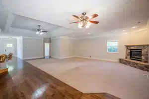 Unfurnished living room with ornamental molding, a raised ceiling, and baseboards