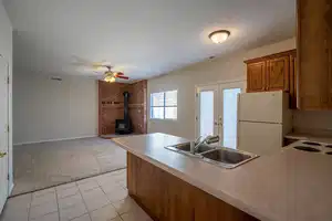 Kitchen with light colored carpet, a sink, visible vents, freestanding refrigerator, and brown cabinets